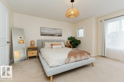 This room features light-colored carpeting, a natural wood nightstand, and a light-colored door - 2828 21 Avenue, Edmonton, AB - Indoor Photo Showing Bedroom