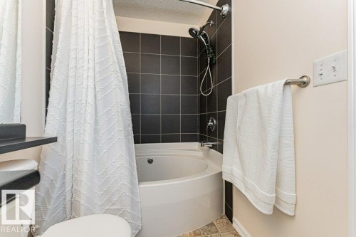 Bathroom featuring a built-in bathtub with dark tiled surround and a shower head - 2828 21 Avenue, Edmonton, AB - Indoor Photo Showing Bathroom