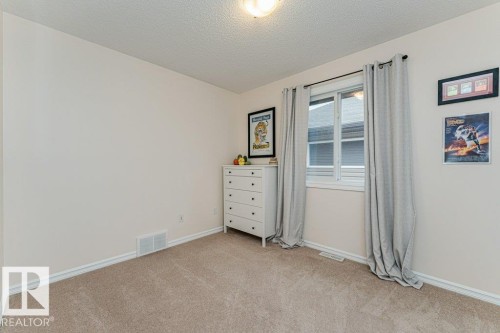 Carpeted room featuring light beige walls, a window with grey curtains, and a ceiling light fixture - 2828 21 Avenue, Edmonton, AB - Indoor