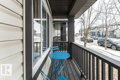 Inviting front porch with a dark railing and columns, offering views of the street and houses - 2828 21 Avenue, Edmonton, AB - Outdoor With Exterior