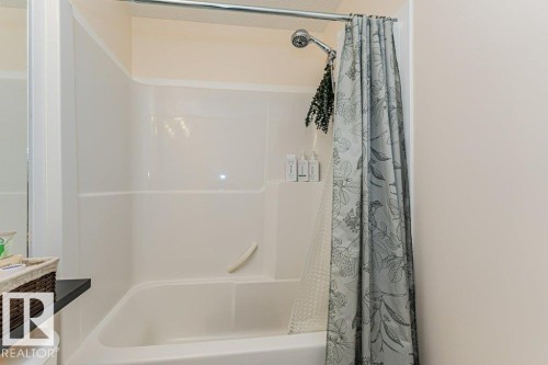 Bathroom featuring a showerhead, a shower curtain rod, and a white bathtub with an integrated shower - 2828 21 Avenue, Edmonton, AB - Indoor Photo Showing Bathroom