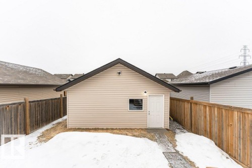 The property features an exterior building with light-colored siding and a dark-shingled roof - 2828 21 Avenue, Edmonton, AB - Outdoor With Exterior
