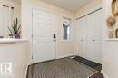 The property features a welcoming entryway with a white paneled door, a side window, and dark hardwood floors - 2828 21 Avenue, Edmonton, AB  - Indoor Photo Showing Other Room 