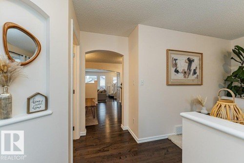 The interior features dark wood flooring, light-colored walls, and an arched doorway - 2828 21 Avenue, Edmonton, AB - Indoor Photo Showing Other Room