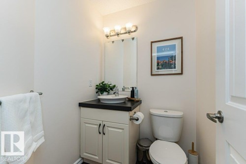 Bathroom featuring a vanity with a dark countertop and a white vessel sink, a mirror, and a toilet - 2828 21 Avenue, Edmonton, AB - Indoor Photo Showing Bathroom