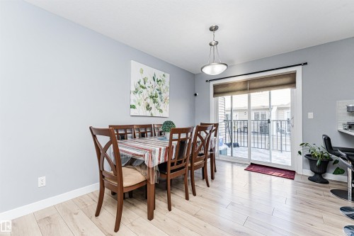 The dining area features light-toned flooring, a light fixture, and a sliding glass door leading to an outdoor space - 35 675 Albany Way Nw, Edmonton, AB - Indoor Photo Showing Dining Room