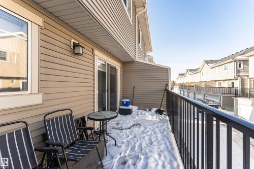 The property features a balcony with a black metal railing and a sliding glass door providing access to the interior - 35 675 Albany Way Nw, Edmonton, AB - Outdoor With Balcony With Exterior