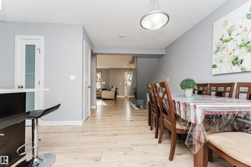 The property features light-toned flooring, light gray walls, and white trim throughout the dining and hallway areas - 35 675 Albany Way Nw, Edmonton, AB - Indoor Photo Showing Dining Room