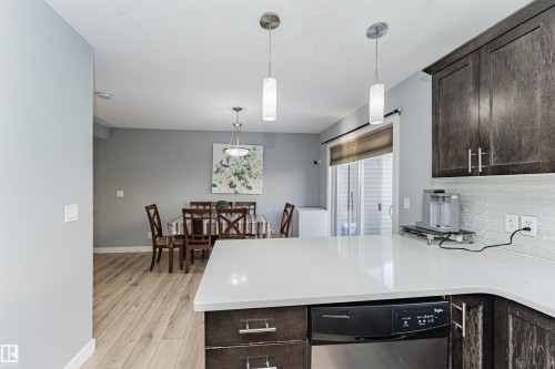 Kitchen featuring dark wood cabinetry, a white countertop, and a white tile backsplash - 35 675 Albany Way Nw, Edmonton, AB - Indoor Photo Showing Kitchen With Upgraded Kitchen