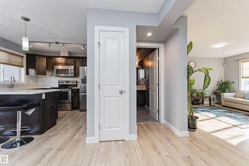 The property features light-colored wood flooring throughout, with a kitchen showcasing dark wood cabinetry, stainless steel appliances, and a white subway tile backsplash - 35 675 Albany Way Nw, Edmonton, AB - Indoor Photo Showing Kitchen