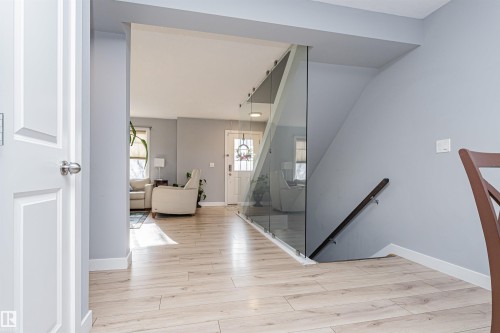 Entryway with light-toned flooring, featuring a modern glass panel partition and a white paneled door - 35 675 Albany Way Nw, Edmonton, AB - Indoor Photo Showing Other Room