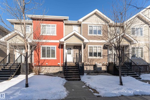The property is a townhouse with a distinct red facade and white trim, featuring two levels of windows - 35 675 Albany Way Nw, Edmonton, AB - Outdoor With Facade