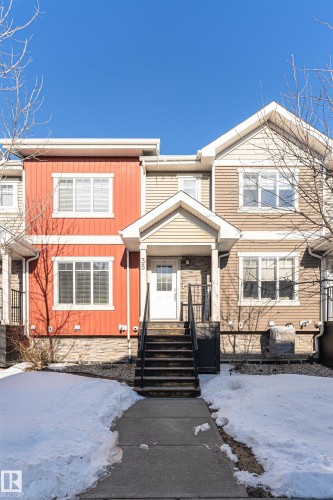 The property features a multi-toned exterior with red and beige siding, complemented by stone detailing on the lower level - 35 675 Albany Way Nw, Edmonton, AB - Outdoor With Facade