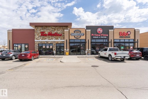 The property features a commercial building with several storefronts, including a coffee shop, barbershop, and restaurants - 35 675 Albany Way Nw, Edmonton, AB - Outdoor