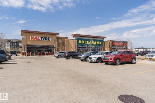 The property features a commercial building with prominent signage for retail businesses - 35 675 Albany Way Nw, Edmonton, AB - Outdoor