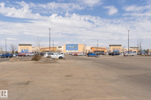 The property is located within a commercial area, featuring a large paved parking lot - 35 675 Albany Way Nw, Edmonton, AB - Outdoor With View