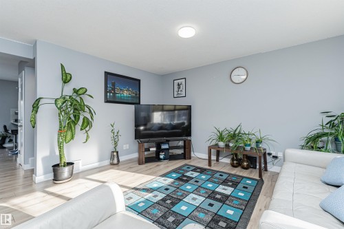 This living area features light-colored flooring, light-colored walls, and a ceiling light fixture - 35 675 Albany Way Nw, Edmonton, AB - Indoor Photo Showing Living Room