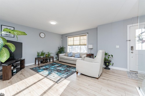 Inviting living space featuring light-toned flooring, light blue walls, and a window with blinds providing natural illumination - 35 675 Albany Way Nw, Edmonton, AB - Indoor Photo Showing Living Room