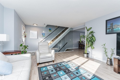 Living space featuring light-colored flooring, a staircase with a glass railing, and a framed piece of artwork on the wall - 35 675 Albany Way Nw, Edmonton, AB - Indoor
