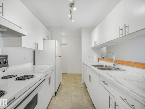 Kitchen featuring white cabinetry with silver-tone hardware, a dual basin stainless steel sink, and a white electric range - 143 10636 120 Street Nw, Edmonton, AB - Indoor Photo Showing Kitchen With Double Sink
