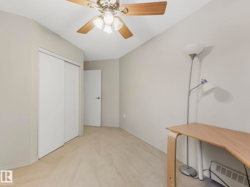 Carpeted room featuring a ceiling fan with light fixture, light gray wall paint, and white trim - 143 10636 120 Street Nw, Edmonton, AB - Indoor Photo Showing Other Room