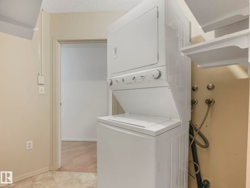 Stackable washer and dryer unit with white appliances - 143 10636 120 Street Nw, Edmonton, AB - Indoor Photo Showing Laundry Room