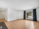 Spacious room featuring wood-finish flooring, white walls, and a large sliding glass door - 143 10636 120 Street Nw, Edmonton, AB  - Indoor Photo Showing Other Room 