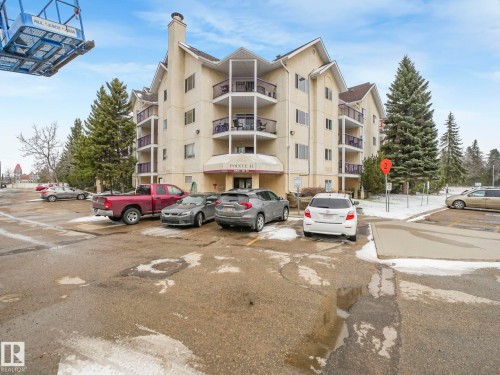 Multi-story residential building featuring a stucco exterior with a prominent entrance canopy and multiple private balconies - 143 10636 120 Street Nw, Edmonton, AB - Outdoor With Facade