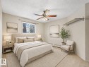 Well-lit interior space featuring a ceiling fan, a window, wall-mounted shelving, and carpet flooring - 143 10636 120 Street Nw, Edmonton, AB  - Indoor Photo Showing Bedroom 