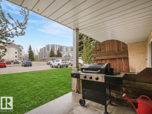 Covered patio space featuring a concrete floor, stone pillar, and a partial privacy screen - 143 10636 120 Street Nw, Edmonton, AB - Outdoor With Deck Patio Veranda With Exterior
