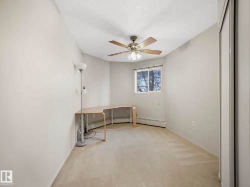 Room featuring neutral wall paint, light-toned carpeting, and a window with a roller shade - 143 10636 120 Street Nw, Edmonton, AB - Indoor Photo Showing Other Room