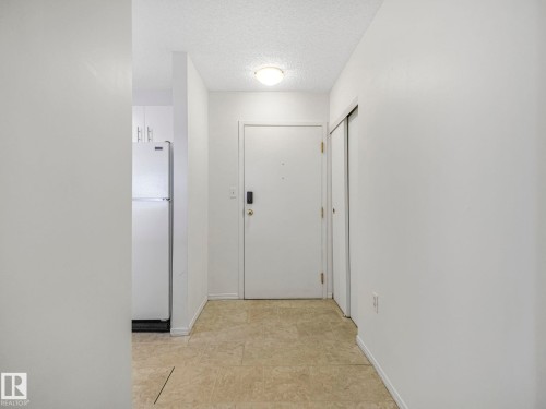 Entryway featuring a solid core door with digital lock, neutral-toned flooring, and a flush mount ceiling light - 143 10636 120 Street Nw, Edmonton, AB - Indoor Photo Showing Other Room