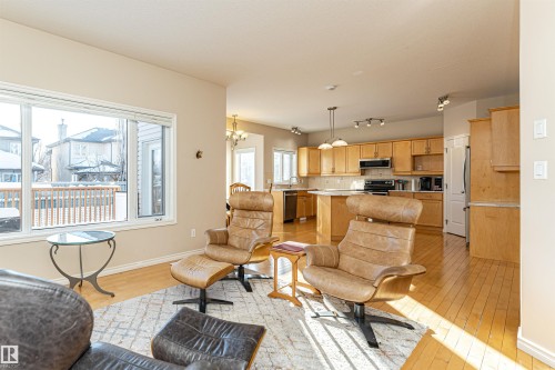Open-concept living space featuring wood-finish flooring, a large window overlooking a wooden deck, and recessed lighting - 1915 126 Street, Edmonton, AB - Indoor Photo Showing Living Room