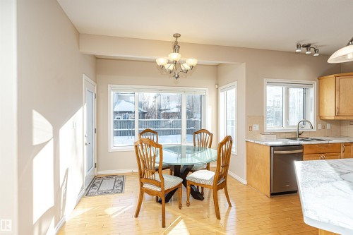 Kitchen and dining area featuring wood-finish flooring, a stainless steel dishwasher, and light wood cabinetry - 1915 126 Street, Edmonton, AB - Indoor Photo Showing Dining Room