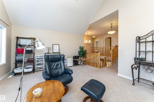 Carpeted upper level featuring a prominent staircase with wood railings and balusters, a vaulted ceiling, and multiple hanging light fixtures - 1915 126 Street, Edmonton, AB - Indoor