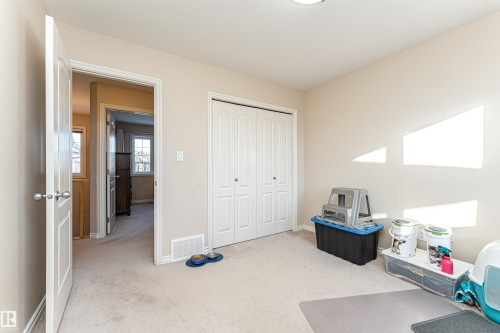 Carpeted room featuring a double-door closet with louvered panels, light neutral wall paint, white trim, and a ceiling light fixture - 1915 126 Street, Edmonton, AB - Indoor