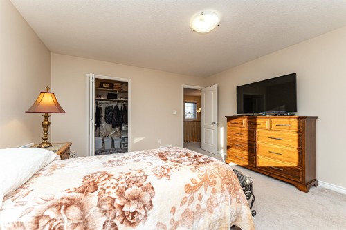 Bedroom featuring neutral wall paint, light-colored carpet flooring, a ceiling-mounted light fixture, and a bi-fold door closet with shelving - 1915 126 Street, Edmonton, AB - Indoor Photo Showing Bedroom