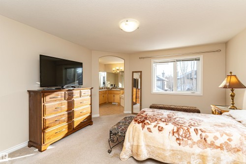 Carpeted bedroom featuring an arched doorway, window, ceiling light fixture, and neutral wall tones - 1915 126 Street, Edmonton, AB - Indoor Photo Showing Bedroom