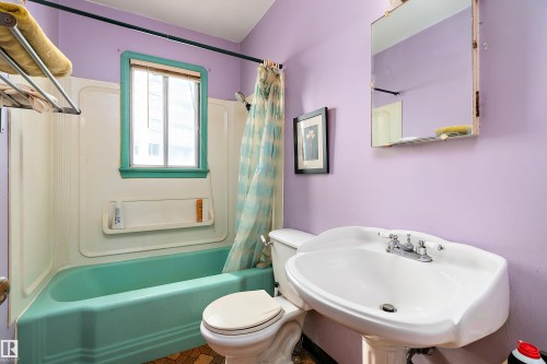 Bathroom featuring a wall-mounted pedestal sink with chrome faucet, a toilet, and a bathtub with an integrated shower surround - 10124 88 Avenue, Edmonton, AB - Indoor Photo Showing Bathroom