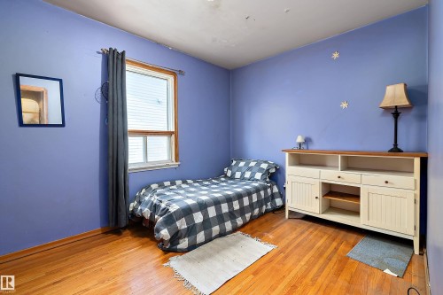 Hardwood-finish flooring with a window featuring horizontal blinds and dark drapery - 10124 88 Avenue, Edmonton, AB - Indoor Photo Showing Bedroom