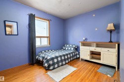 Hardwood-finish flooring with a window featuring horizontal blinds and dark drapery - 