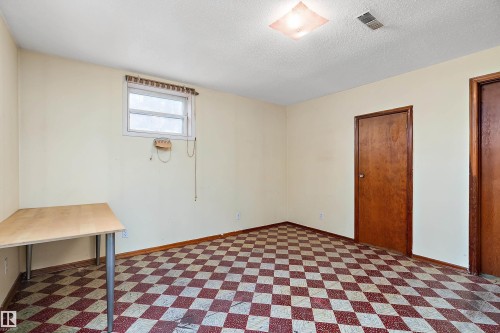 Room featuring checkerboard pattern flooring, a window with horizontal blinds, and two wood-finish doors - 10124 88 Avenue, Edmonton, AB - Indoor Photo Showing Bedroom