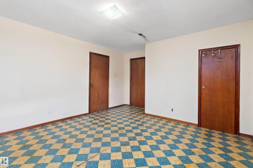 Room featuring checkered flooring, three solid wood doors, and white painted walls - 10124 88 Avenue, Edmonton, AB - Indoor