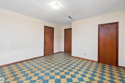 Room featuring checkered flooring, three solid wood doors, and white painted walls - 