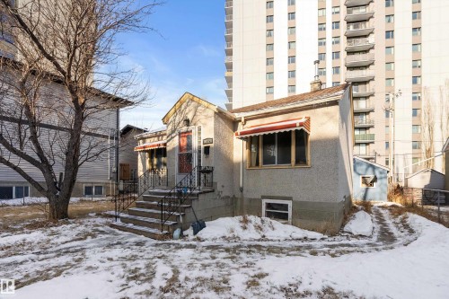 Stucco exterior with a peaked roofline and front entry porch featuring black wrought iron railings - 10124 88 Avenue, Edmonton, AB - Outdoor With Facade