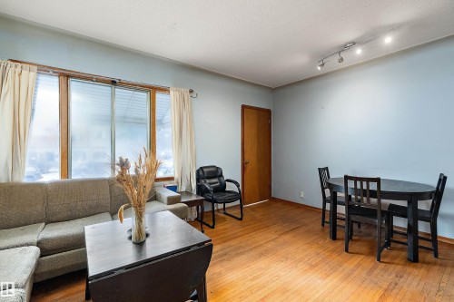Open-concept living area with wood-finish flooring, track lighting, and a prominent window with wood trim - 10124 88 Avenue, Edmonton, AB - Indoor Photo Showing Living Room