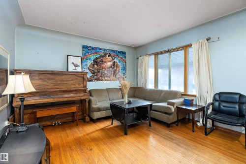 Hardwood flooring throughout featuring a large window with natural wood trim - 10124 88 Avenue, Edmonton, AB - Indoor Photo Showing Living Room
