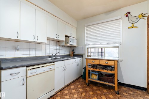 Kitchen featuring white cabinetry, a double basin stainless steel sink, tile backsplash, and durable countertop surfaces - 10124 88 Avenue, Edmonton, AB - Indoor Photo Showing Kitchen With Double Sink
