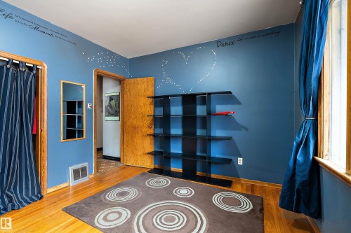 Hardwood flooring extends throughout this room, featuring a built-in shelving unit, a window with natural wood trim, and a doorway with a natural wood door frame - 10124 88 Avenue, Edmonton, AB - Indoor