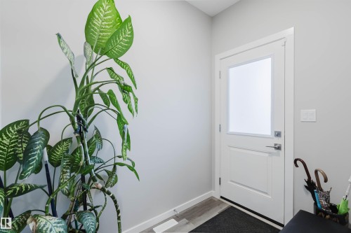 Entryway featuring a white paneled door with frosted glass insert, brushed nickel hardware, light wood-finish flooring, and crisp white baseboards - 343 Edgemont Drive, Edmonton, AB - Indoor Photo Showing Other Room
